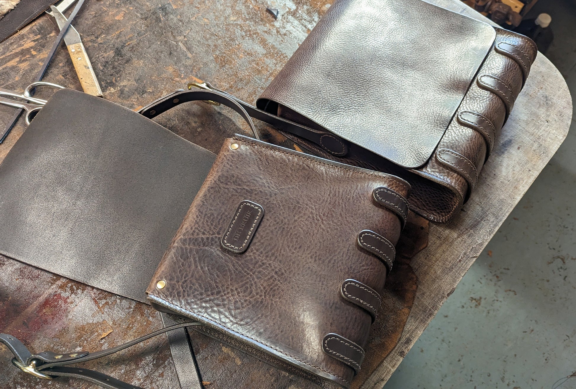 Two leather messenger bags side by side, one open.