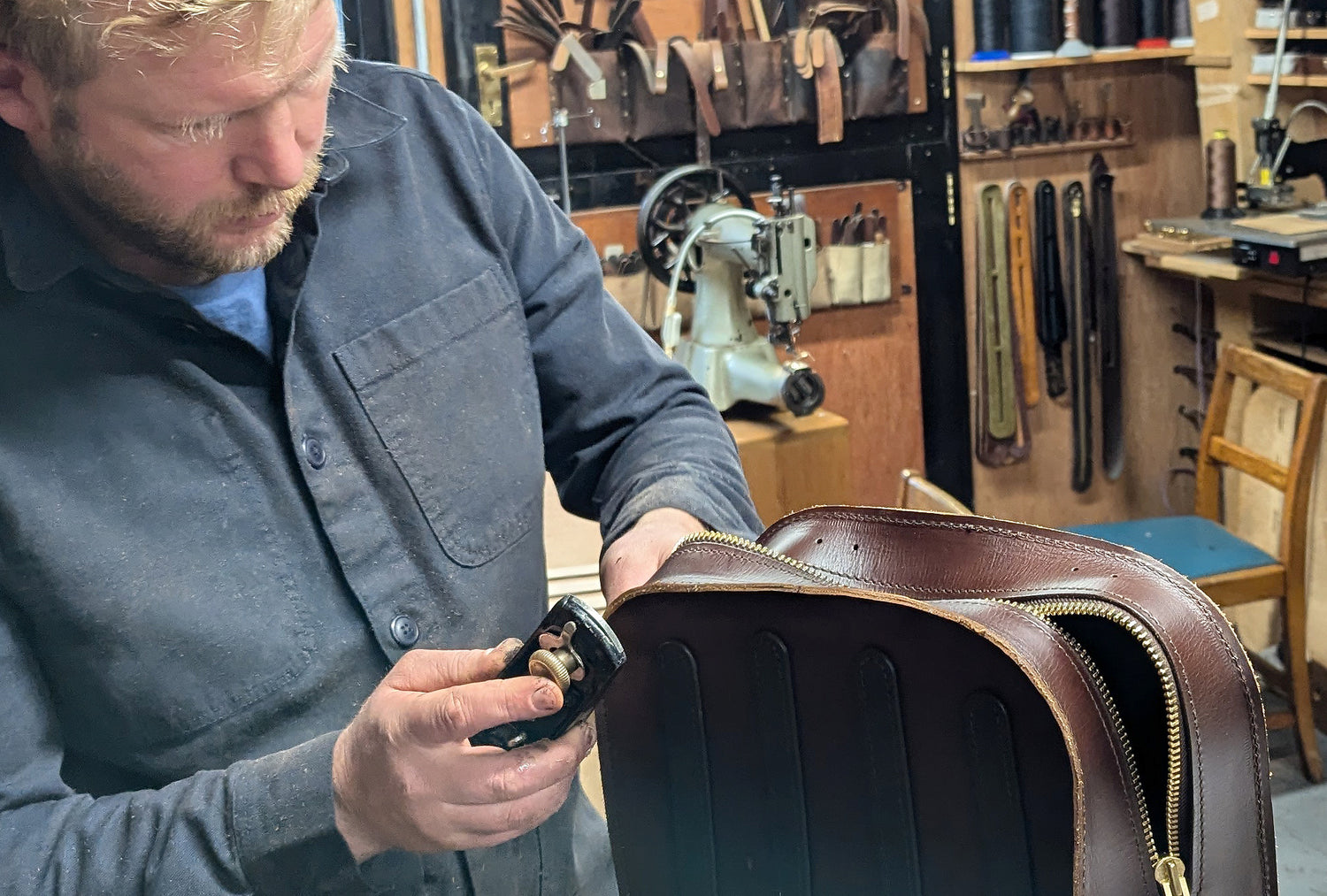 Leather crafts man working on a brown leather bag in workshop